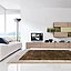 Helles Wohnzimmer mit weißem Sofa, bodentiefen Fenstern, Lowboard mit Fernseher und modularen Holz‑/grünen Regalen; Teppich davor