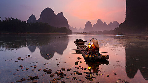 Man on a raft on a lake in the mountains at sunset