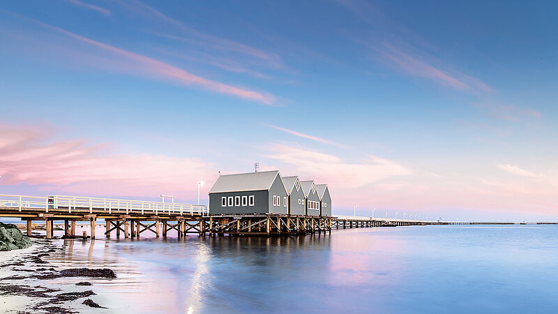 Three houses on a pier in the sea at sunset