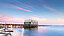 Three houses on a pier in the sea at sunset
